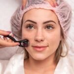 A woman wearing a pink hair cap receives a professional-grade derma roller treatment for precise skin care results.