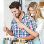 Woman using ultrasonic toothbrush while hugging her husband in the kitchen, showcasing ease of use.