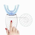 Close-up of red-polished hand pressing the power button on a U-shaped toothbrush.