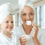 Mom using ultrasonic toothbrush in serene setting with child, showcasing whitening benefits for adults.
