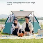 Family enjoying a picnic outside a spacious automatic pop-up camping tent near a scenic lakeside.