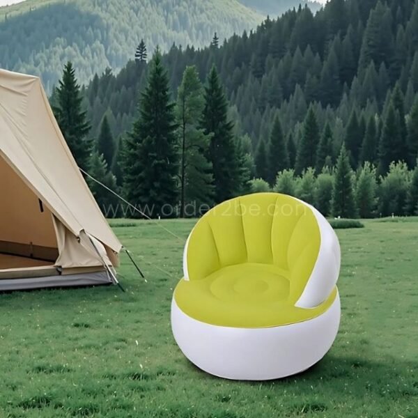 A green inflatable chair set up near a tent on a grassy field.