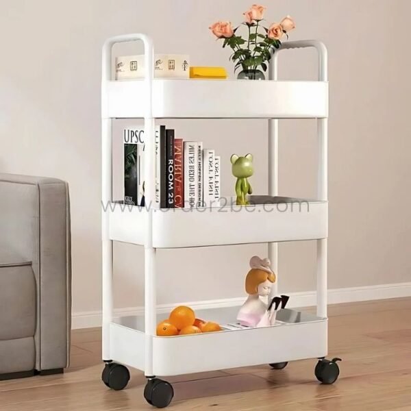 White 3-tier rolling organizer rack holding books, decorative items, and fruit in a cozy living room setting.