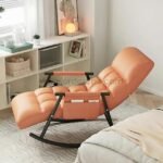 Orange lounge chair in a softly lit bedroom, styled with blankets, candles, and ambient lighting.