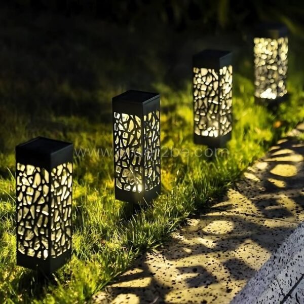 A row of creative solar garden lights with intricate designs softly illuminates a tranquil garden pathway at night.