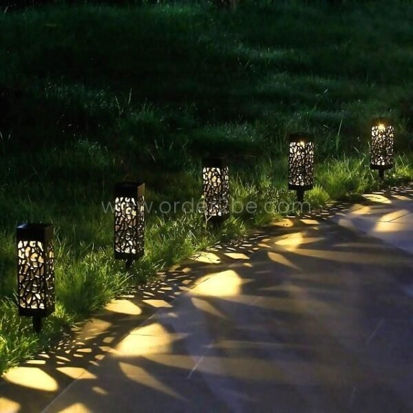 A row of creative solar garden lights casting intricate shadows along a stone pathway, creating a mesmerizing nighttime scene.