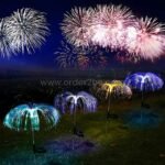 Jellyfish solar garden lights glowing in a field beneath a real fireworks display, colors reflecting in sync.