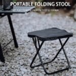 Black portable folding stool set up outdoors on gravel, demonstrating its stability and high load-bearing capacity.