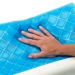 A hand presses gently into the blue gel layer of the Restform Pillow, revealing its plush, cooling surface.