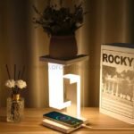 Modern dimmable desk lamp with wireless charging, flowers, and books on a cozy desk.