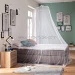 White bed mosquito net hanging over a sleek modern bed with minimal decor and travel-inspired wall art.