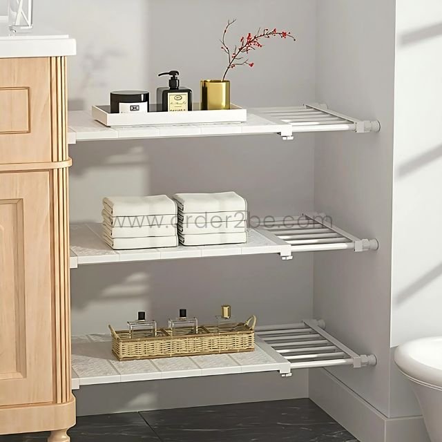 Adjustable Shelf Organizer installed between a bathroom cabinet and wall, holding towels and toiletries.