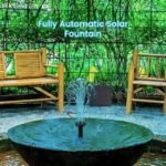 Fully automatic solar-powered water fountain placed in a calm outdoor nook surrounded by bamboo and foliage.