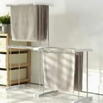 2-Tier laundry drying rack next to a single-tier version, placed in a tidy space with wooden shelves and plants.