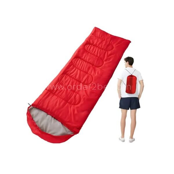 Red portable sleeping bag shown with a traveler standing next to it, highlighting its vibrant color and compact profile.