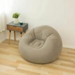 Beige inflatable bean bag chair next to a small side table, lightweight and easy to move.