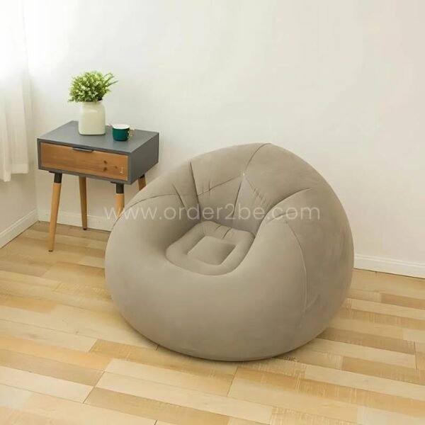 Beige inflatable bean bag chair next to a small side table, lightweight and easy to move.