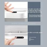 A finger presses the manual open button on the lid of the touchless trash can.